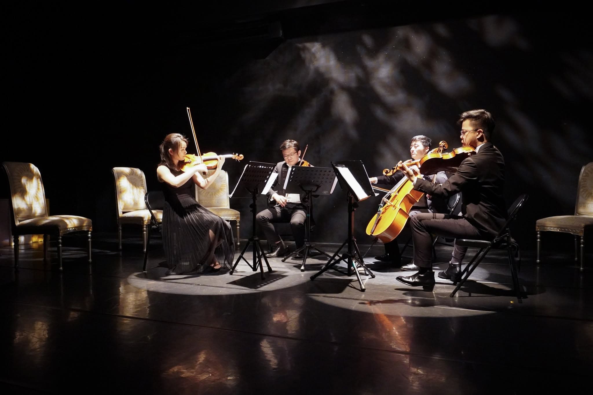 A string quartet performs under theatrical light.